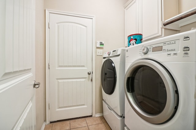 washroom featuring washer and dryer, light tile patterned floors, and cabinets