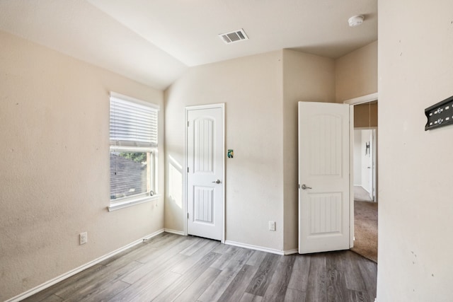 unfurnished bedroom with light hardwood / wood-style flooring and lofted ceiling