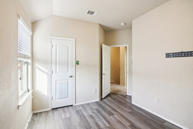 unfurnished bedroom with vaulted ceiling and light hardwood / wood-style flooring