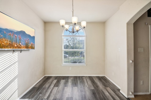 unfurnished dining area with dark wood-type flooring and an inviting chandelier