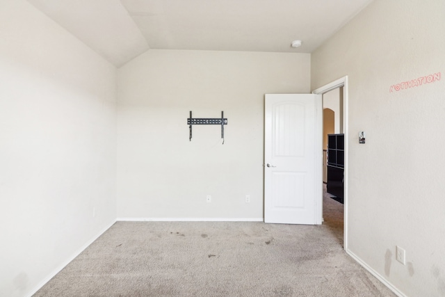 unfurnished room featuring lofted ceiling and light carpet