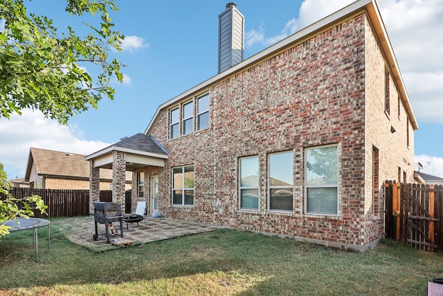 rear view of property with a patio, a trampoline, and a lawn