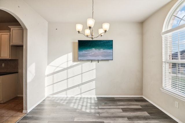 unfurnished dining area featuring dark wood-type flooring and a notable chandelier