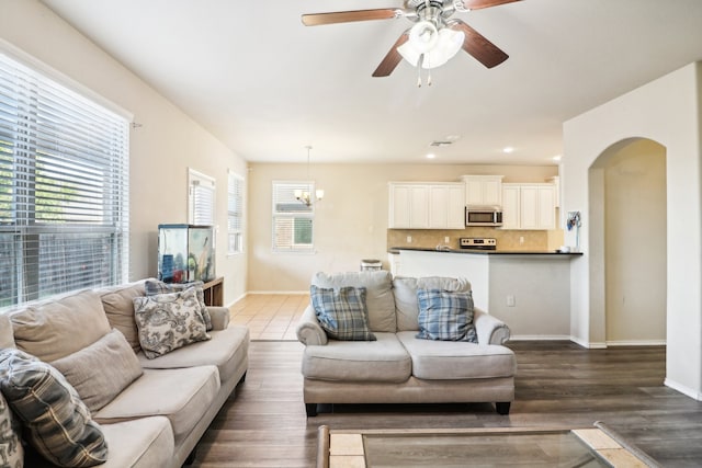 living room featuring dark wood-type flooring and ceiling fan with notable chandelier