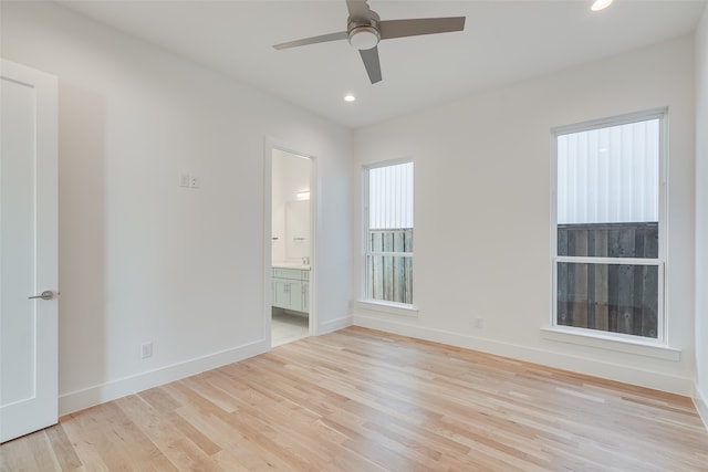 interior space with light hardwood / wood-style flooring, connected bathroom, and ceiling fan