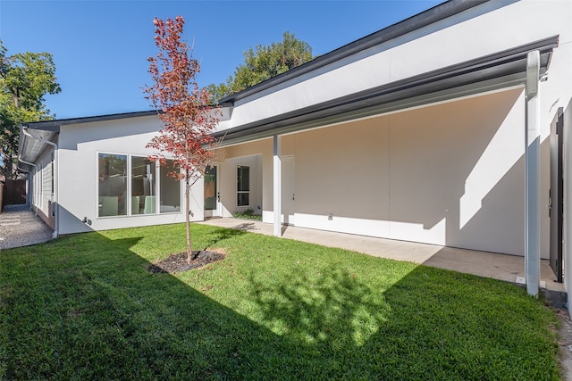 rear view of house featuring a yard and a patio