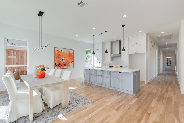 kitchen with a spacious island, white cabinets, light wood-type flooring, and pendant lighting