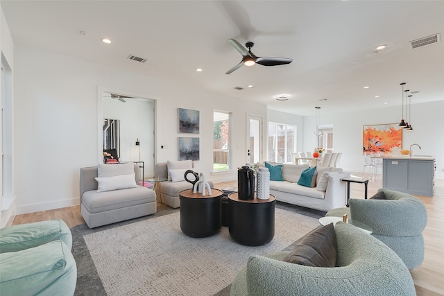 living room with sink, ceiling fan, and light hardwood / wood-style flooring