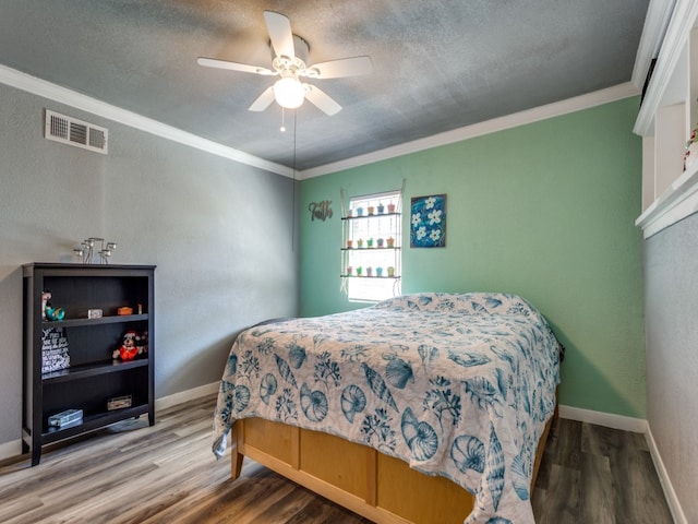 bedroom featuring ceiling fan, a textured ceiling, wood-type flooring, and ornamental molding