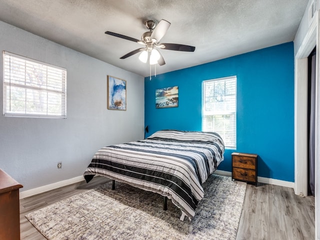 bedroom featuring light hardwood / wood-style flooring, a textured ceiling, and ceiling fan