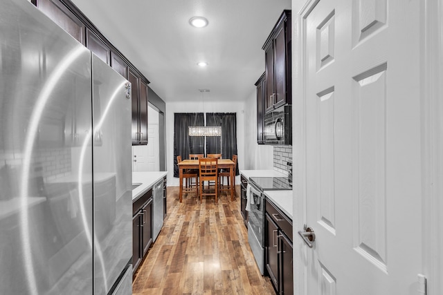 kitchen featuring dark brown cabinets, appliances with stainless steel finishes, light hardwood / wood-style flooring, and pendant lighting