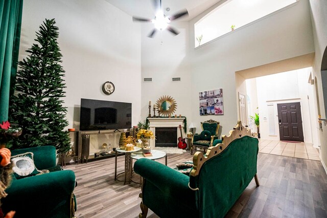 living room with a towering ceiling, hardwood / wood-style flooring, and ceiling fan