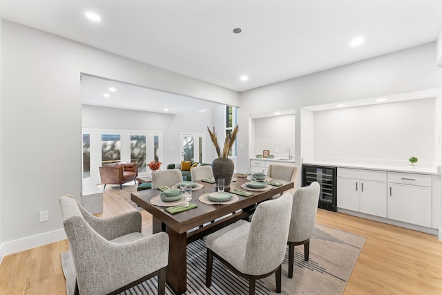 dining area with wine cooler, french doors, indoor wet bar, and light hardwood / wood-style flooring