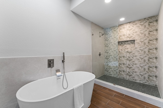 bathroom featuring shower with separate bathtub and tile walls