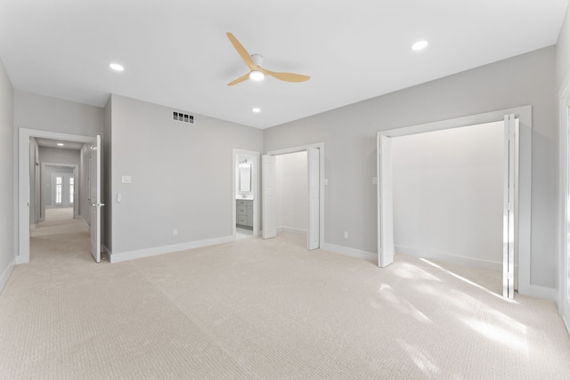 unfurnished bedroom featuring ceiling fan, ensuite bathroom, and light colored carpet