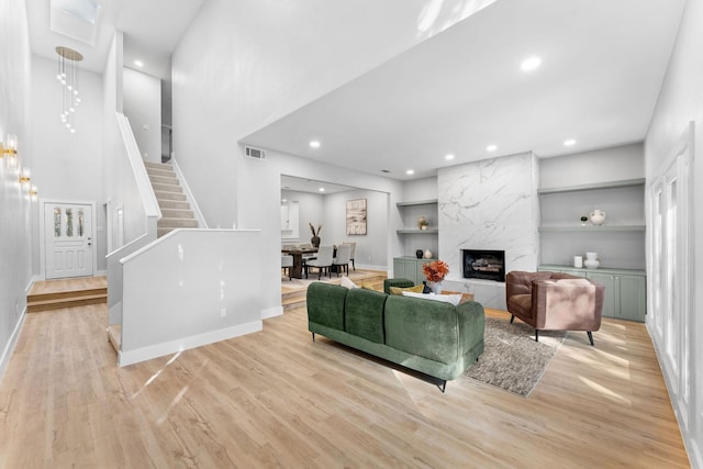 living room featuring light wood-type flooring, a fireplace, and built in shelves