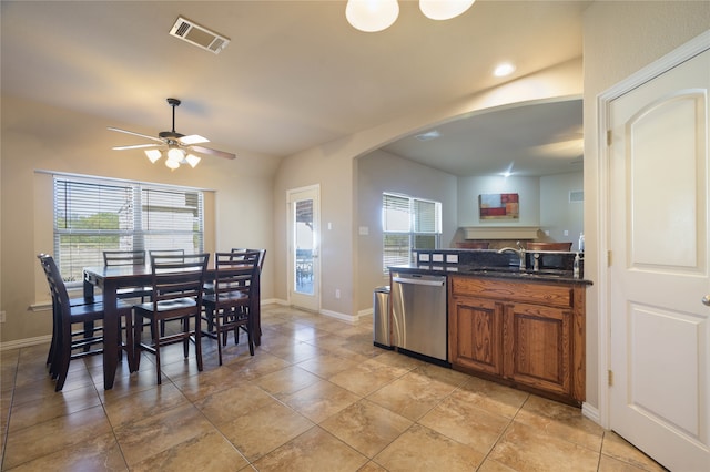 kitchen with light tile patterned floors, ceiling fan, dark stone counters, dishwasher, and sink