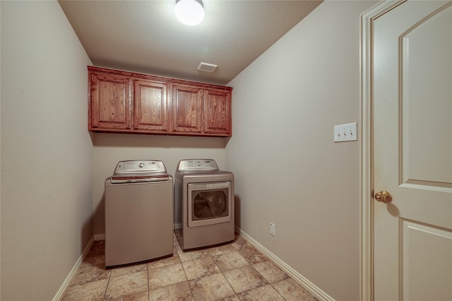 washroom featuring a textured ceiling, cabinets, and washer and clothes dryer