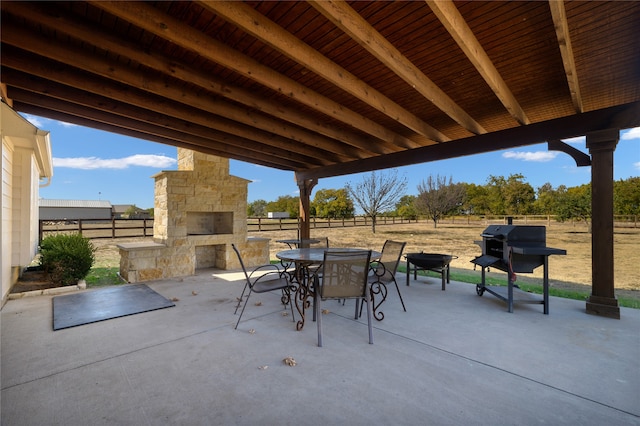 view of patio featuring a rural view, grilling area, and an outdoor stone fireplace