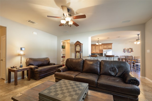 tiled living room featuring built in features and ceiling fan with notable chandelier