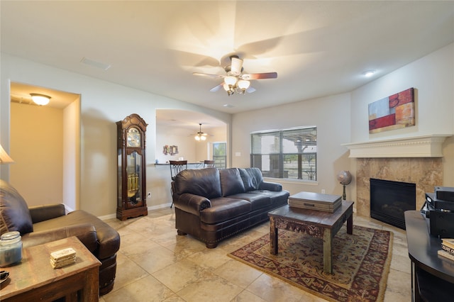 living room with a tiled fireplace, light tile patterned floors, and ceiling fan