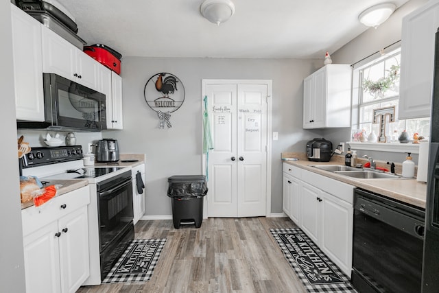 kitchen featuring white cabinetry, black appliances, sink, and light wood-type flooring