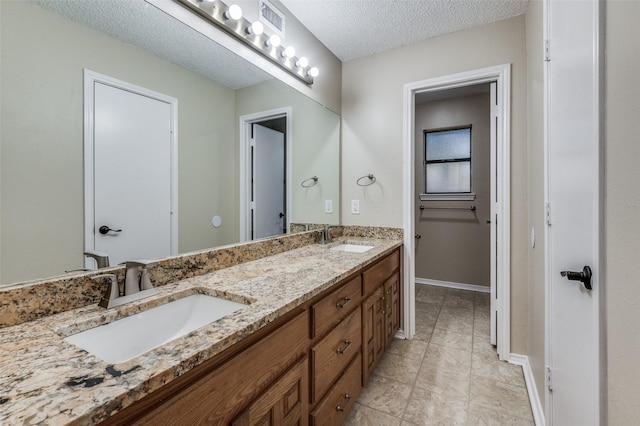 bathroom featuring tile patterned floors, vanity, and a textured ceiling