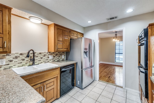 kitchen featuring black appliances, sink, light tile patterned floors, a textured ceiling, and decorative light fixtures