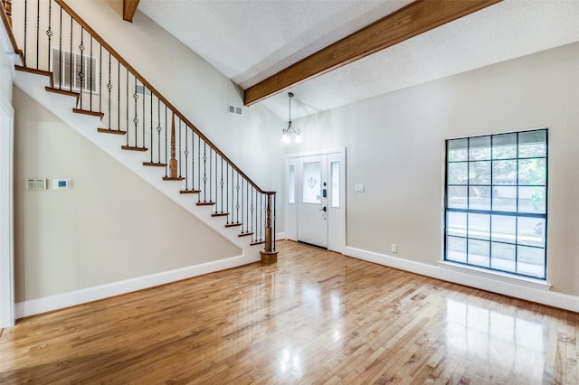 entryway with beam ceiling, wood-type flooring, a textured ceiling, and a healthy amount of sunlight