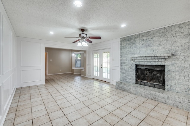 unfurnished living room with light tile patterned floors, a textured ceiling, a fireplace, and ceiling fan