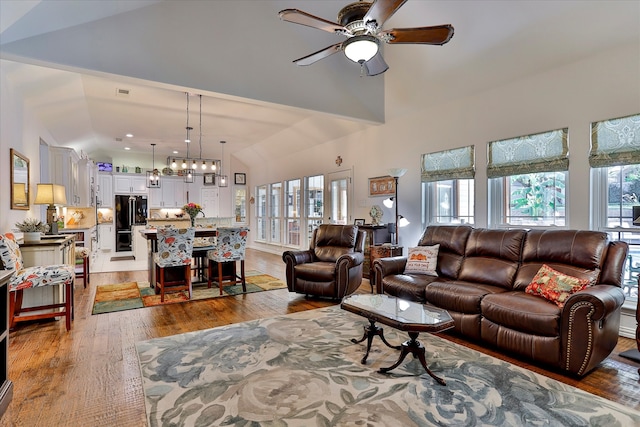 living room with dark hardwood / wood-style floors, ceiling fan with notable chandelier, plenty of natural light, and vaulted ceiling