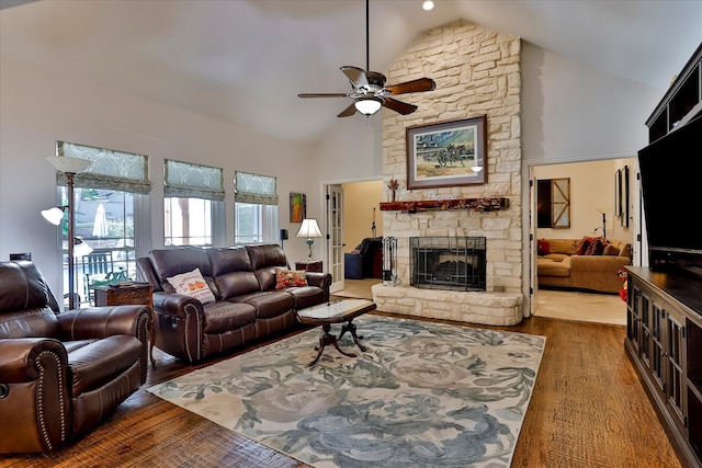 living room featuring high vaulted ceiling, a stone fireplace, dark hardwood / wood-style flooring, and ceiling fan