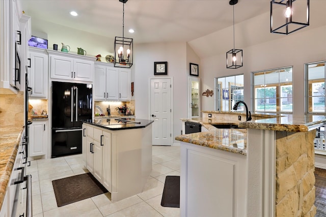 kitchen featuring lofted ceiling, a large island with sink, white cabinetry, black appliances, and pendant lighting