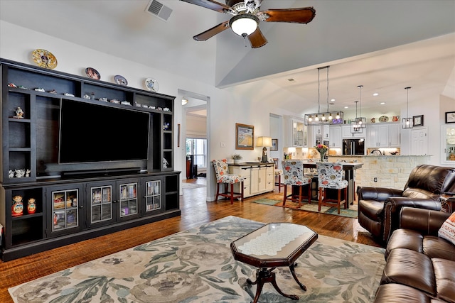 living room with dark wood-type flooring, lofted ceiling, and ceiling fan with notable chandelier