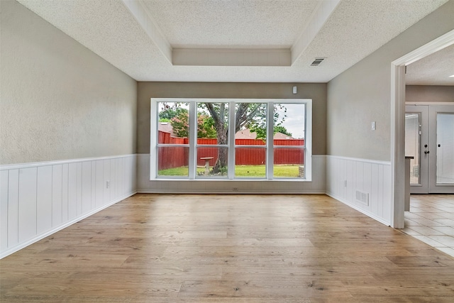 unfurnished room featuring french doors, a textured ceiling, and light wood-type flooring