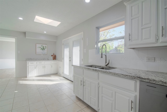 kitchen with sink, white cabinetry, and a skylight