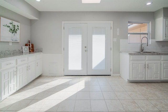 interior space with light tile patterned flooring, french doors, and sink