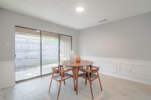 dining space with a textured ceiling and light wood-type flooring