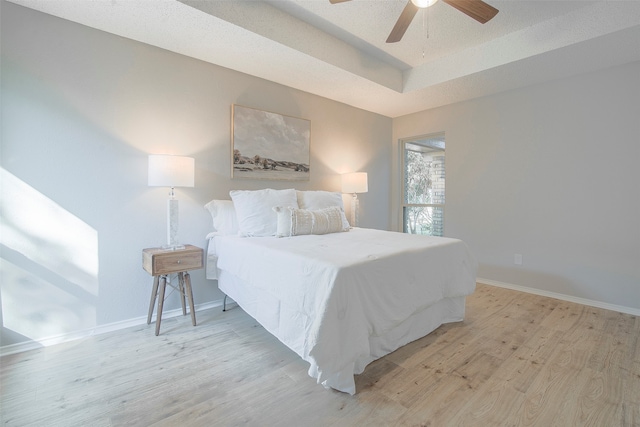 bedroom with ceiling fan, a textured ceiling, and light hardwood / wood-style flooring