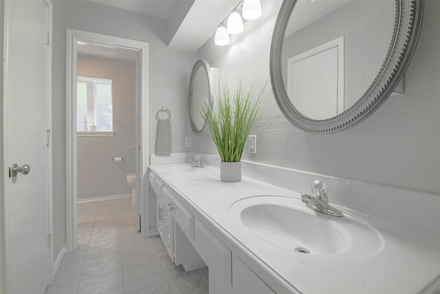 bathroom with toilet, vanity, and tile patterned flooring