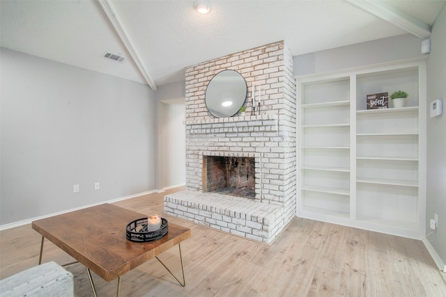 living room featuring lofted ceiling with beams, a fireplace, a textured ceiling, and light hardwood / wood-style floors