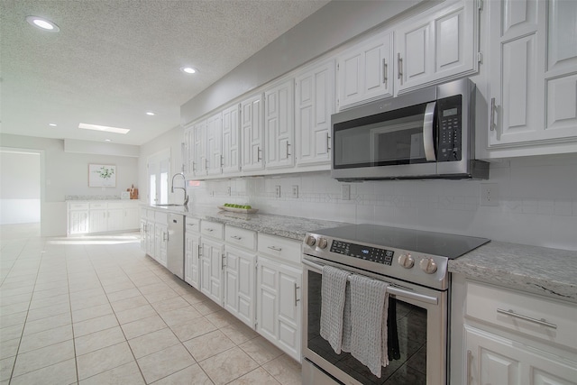 kitchen featuring appliances with stainless steel finishes, white cabinets, sink, and backsplash