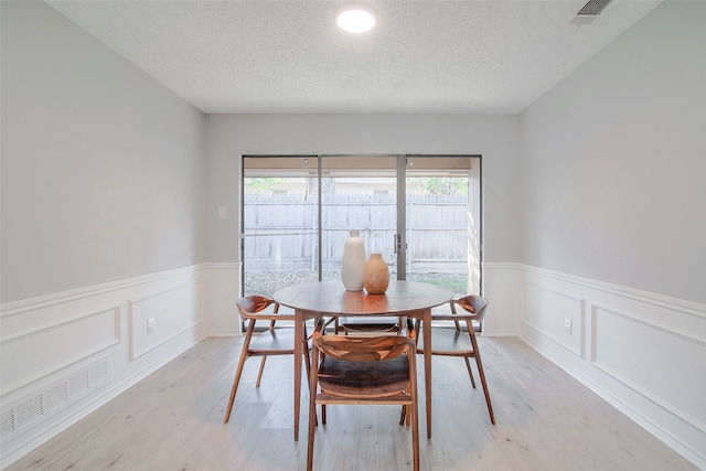 dining area with a textured ceiling, light hardwood / wood-style flooring, and plenty of natural light