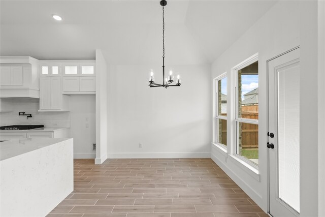 unfurnished dining area with light hardwood / wood-style floors, a healthy amount of sunlight, and a chandelier