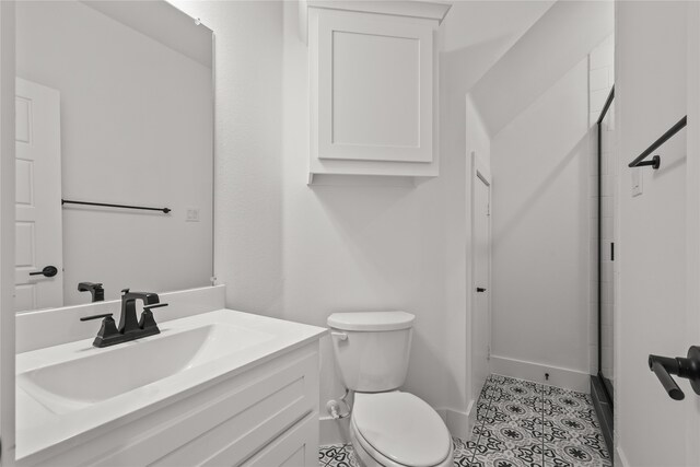 bathroom with toilet, tile patterned flooring, vanity, and a shower with door