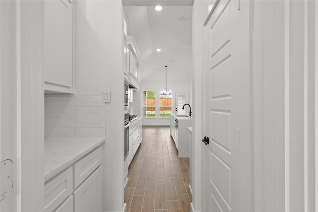 hallway featuring sink, light hardwood / wood-style floors, and a chandelier