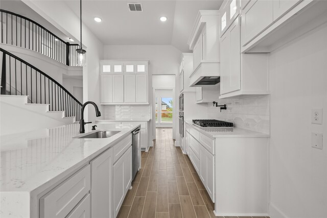 kitchen featuring light stone countertops, appliances with stainless steel finishes, sink, white cabinetry, and pendant lighting