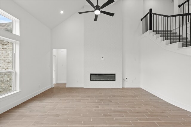 unfurnished living room featuring light wood-type flooring, high vaulted ceiling, and ceiling fan