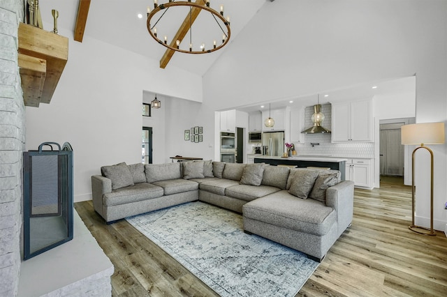 living room with an inviting chandelier, light hardwood / wood-style flooring, beam ceiling, and high vaulted ceiling