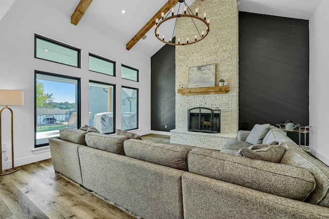 living room featuring beamed ceiling, wood-type flooring, a chandelier, a fireplace, and high vaulted ceiling